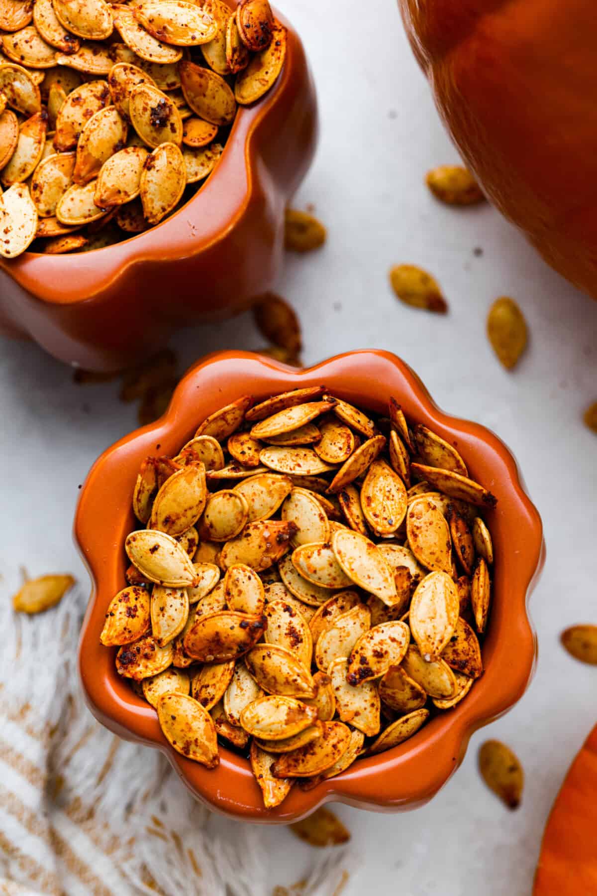 Overhead shot of roasted pumpkin seeds in a cute pumpkin container. 