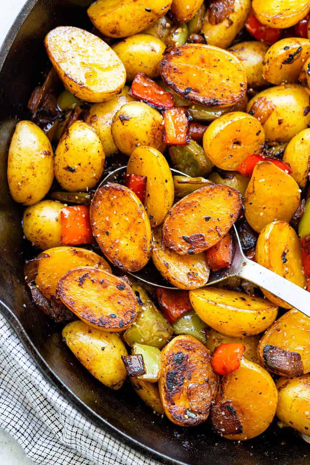 scooping halved potatoes out of a cast iron skillet