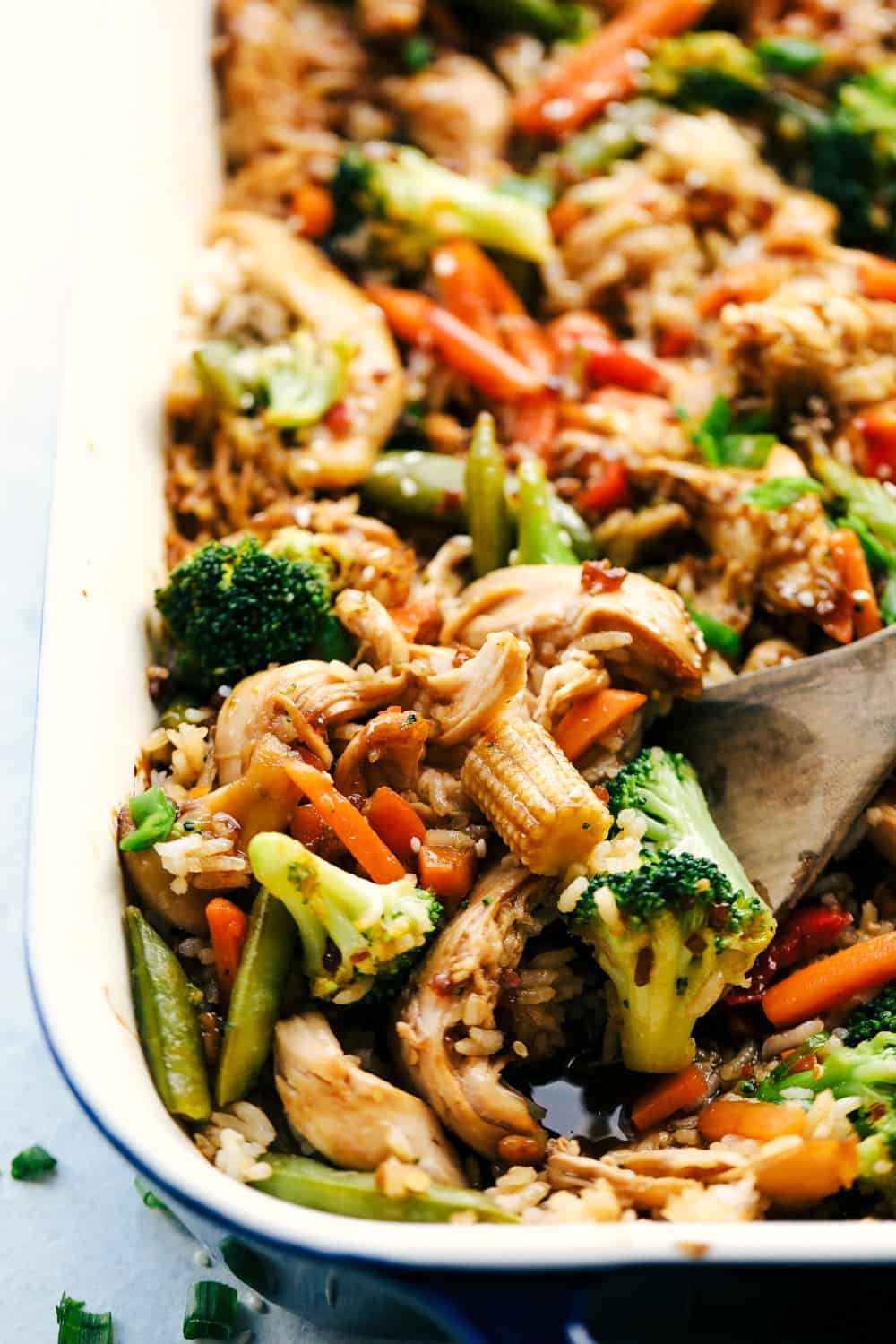 Scooping up chicken, vegetables, and rice with a wooden spoon.