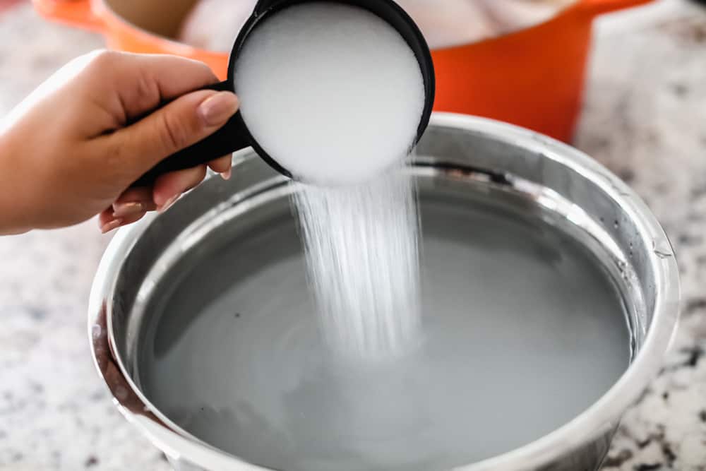 Adding salt to a bowl of water.