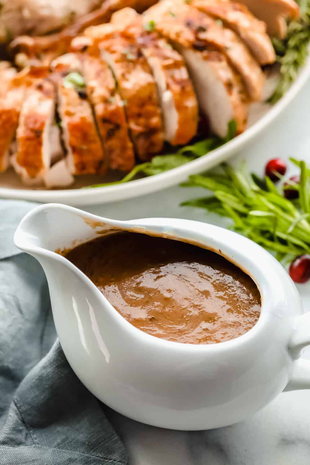 Turkey gravy with turkey next to it in a serving dish. 