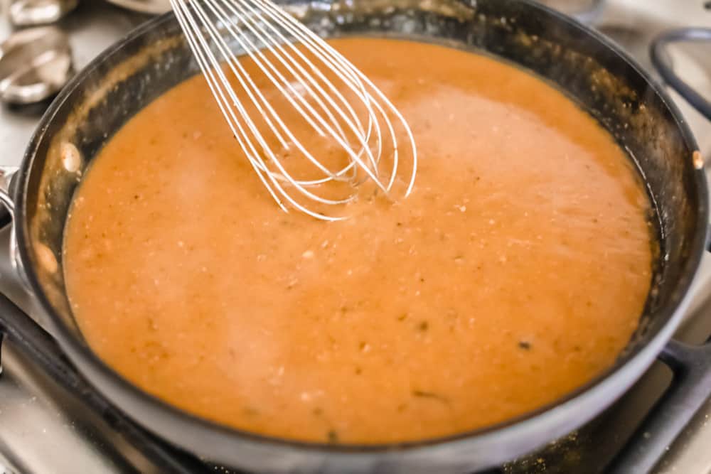 Stirring the turkey gravy in a sauce pan with a whisk.