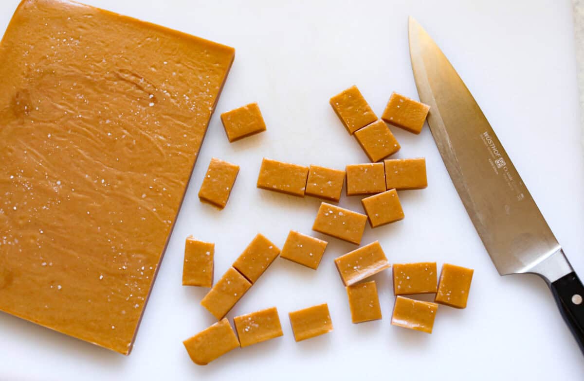 Overhead shot of cut up caramels next to the slab of caramel. 