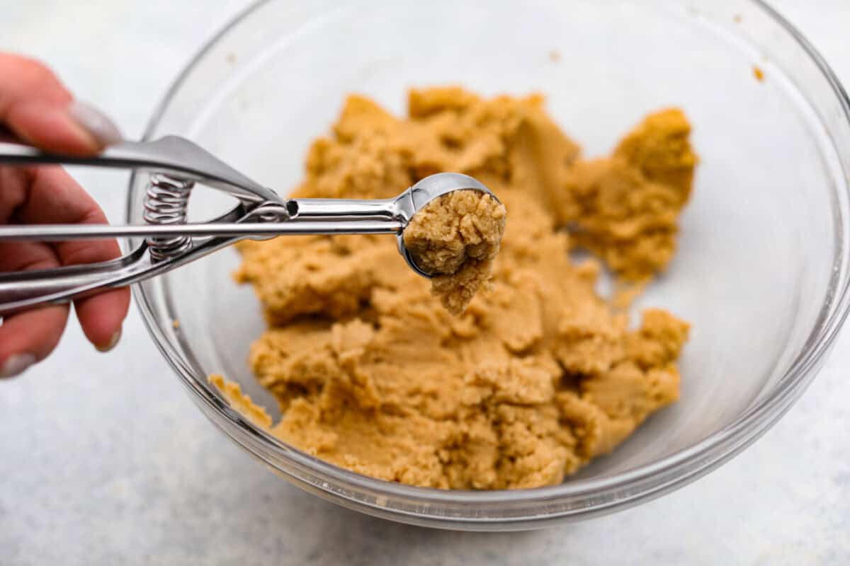 Overhead shot of someone using a cookie scoop to scoop portions of dough. 