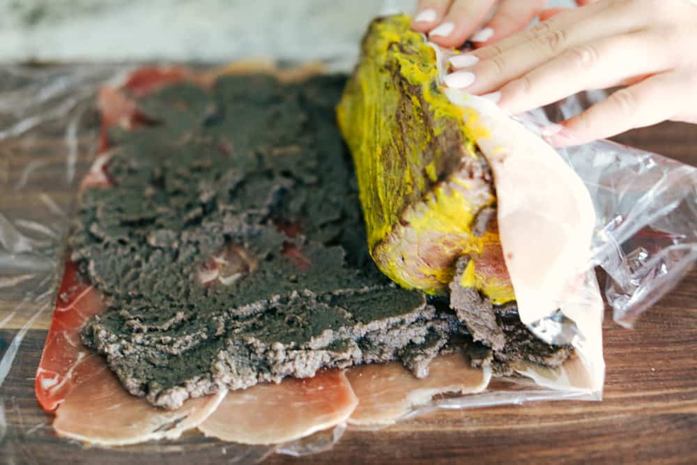 Beef being rolled into the mushroom and meat layers 