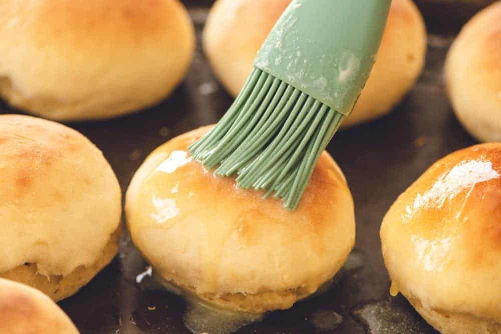 Brushing melted butter on rolls.