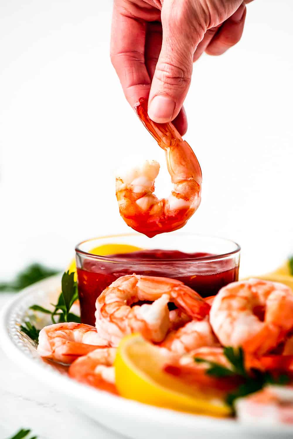 shrimp being dipped in cocktail sauce 