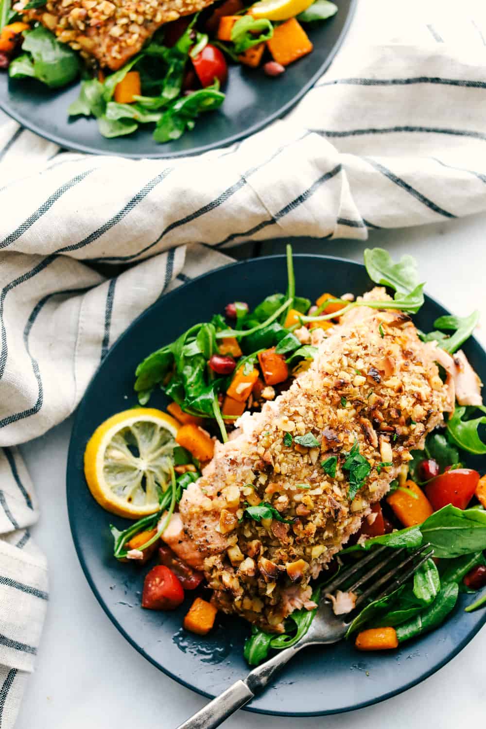 Walnut crusted maple salmon on a plate with a side salad. 