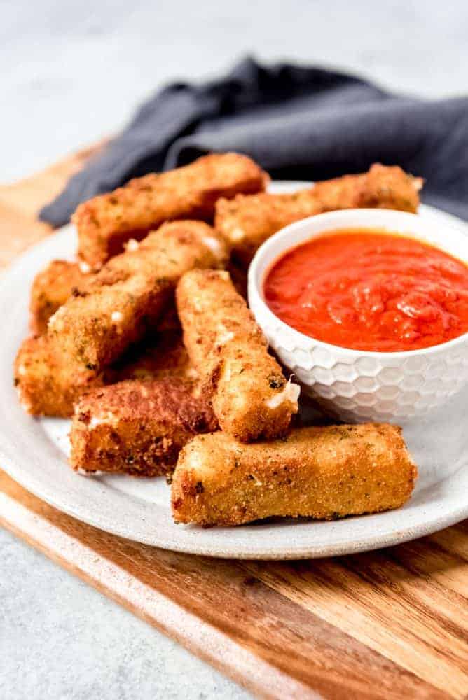 An image of fried mozzarella sticks on a plate with marinara dipping sauce.