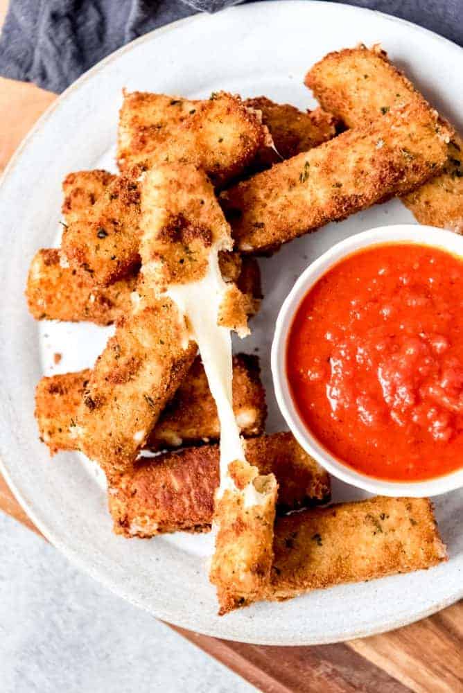 An image of stretchy mozzarella cheese sticks being pulled apart.