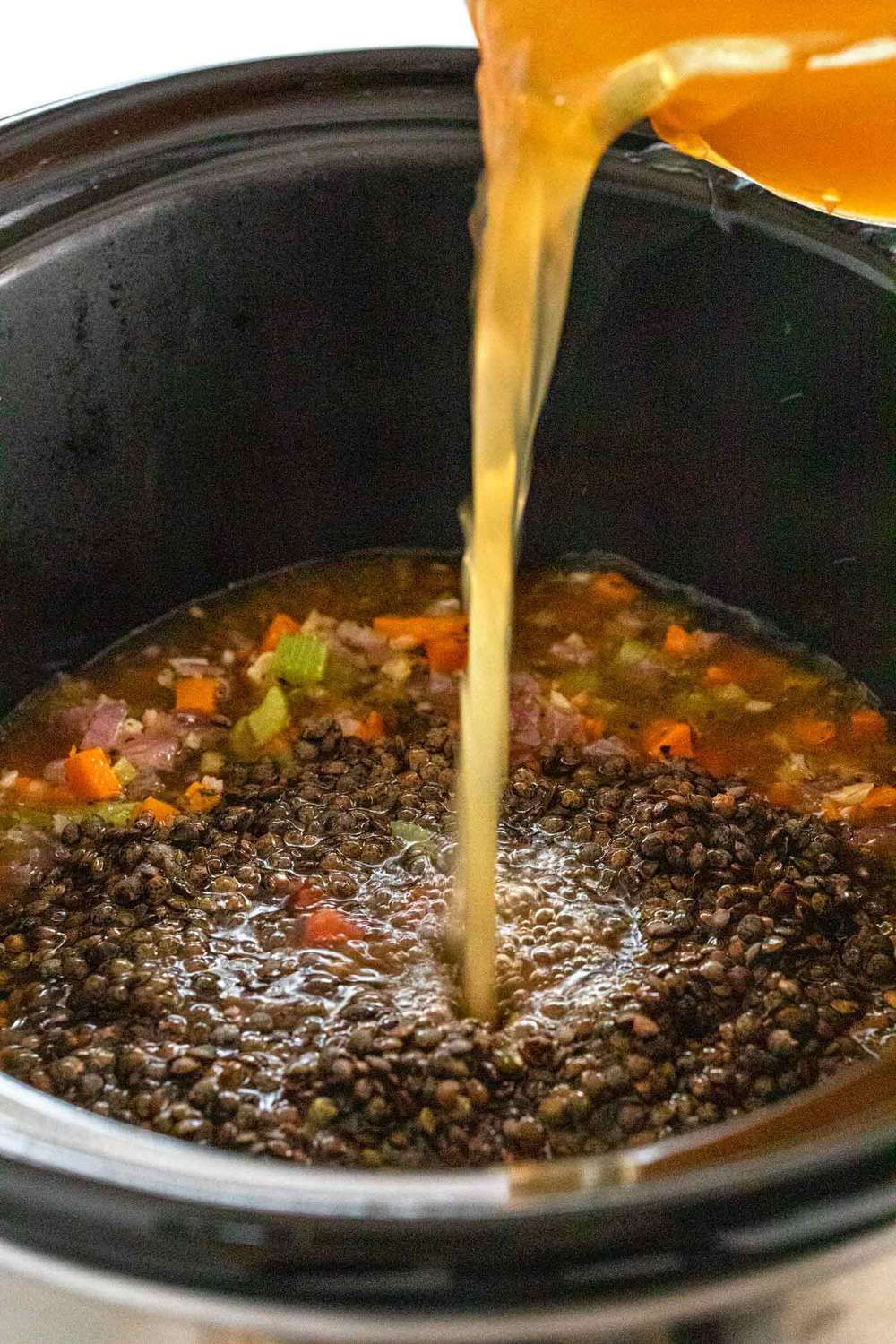 pouring soup liquid into a slow cooker