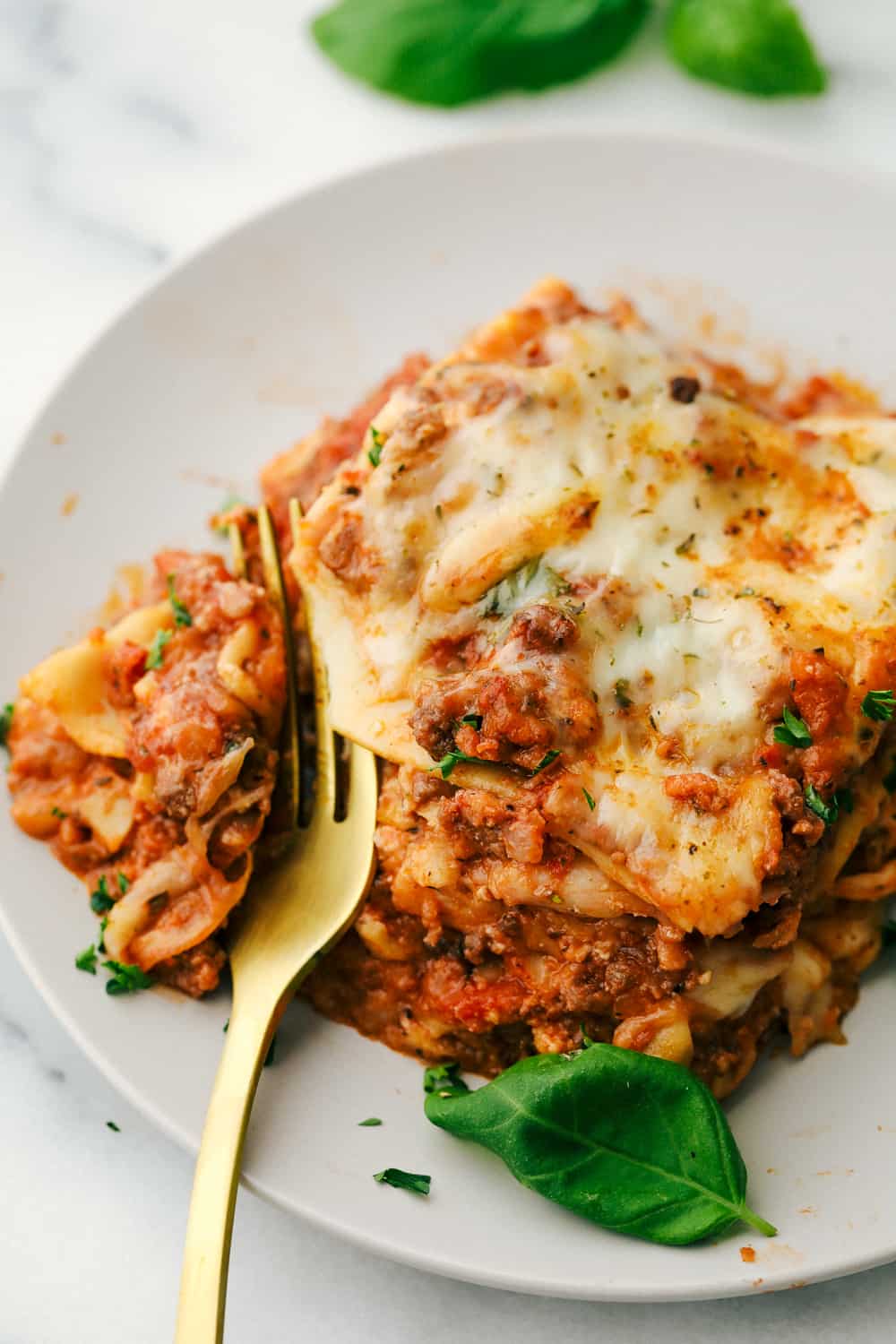 Lasagna on a plate with a gold fork.