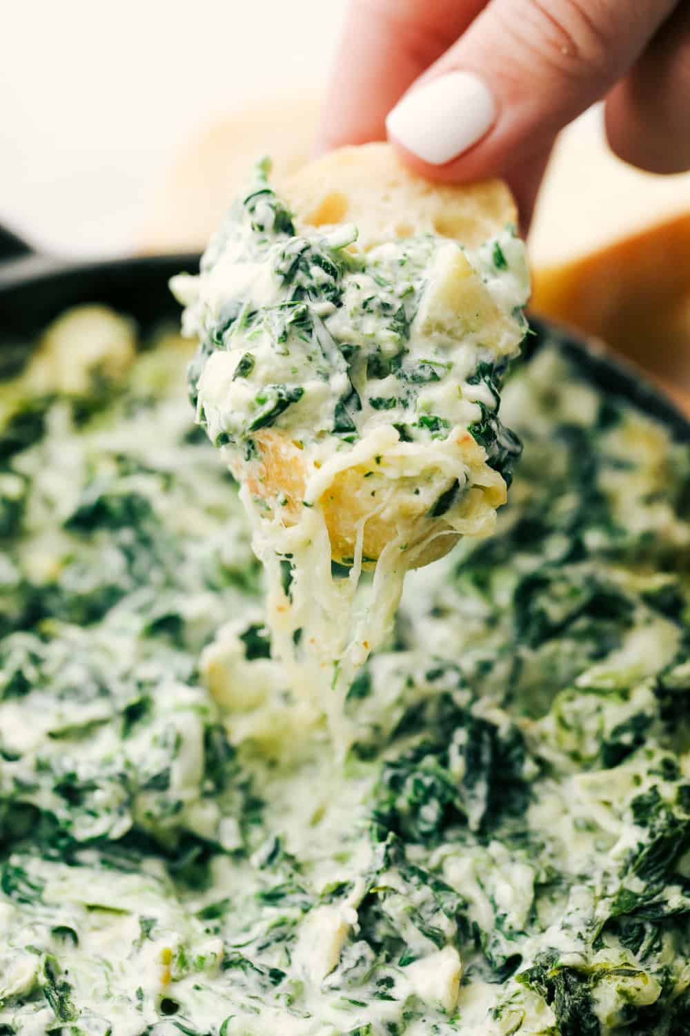 Spinach artichoke dip with bread dipped in it. 