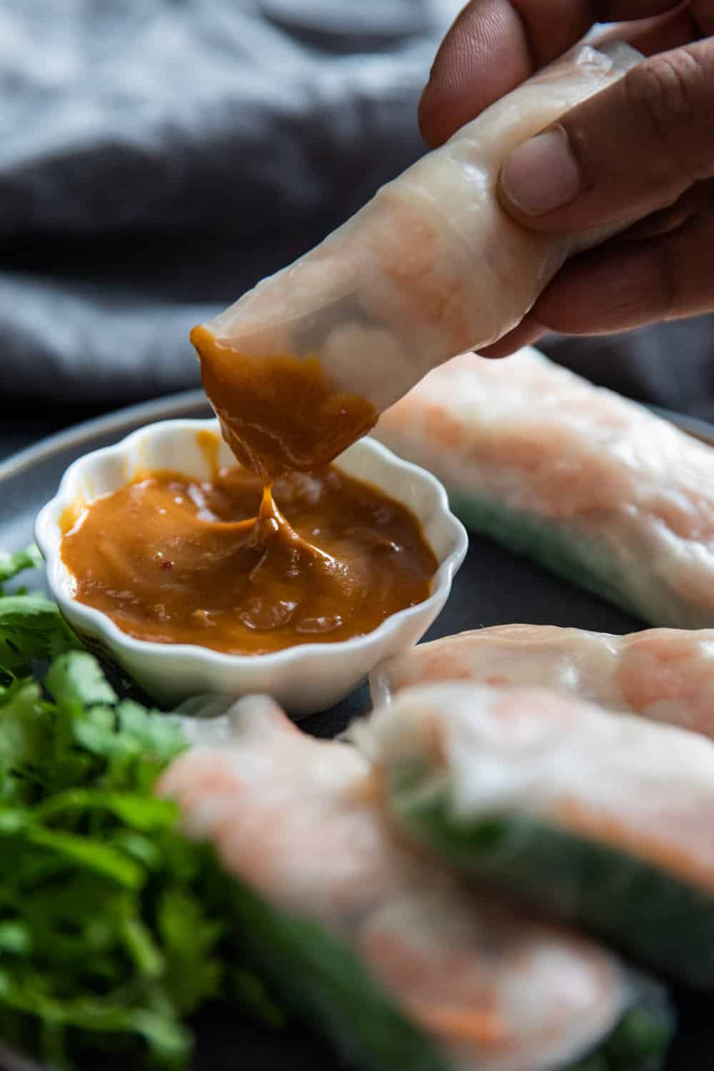 Shrimp spring rolls being dipped in a sauce. 