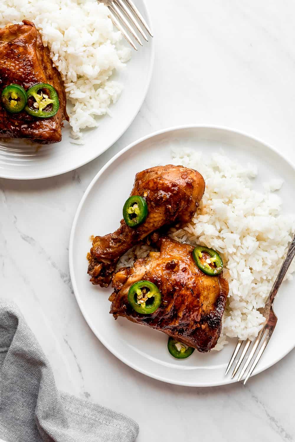 Chicken Adobo on a plate with rice and garnished with jalapeños 