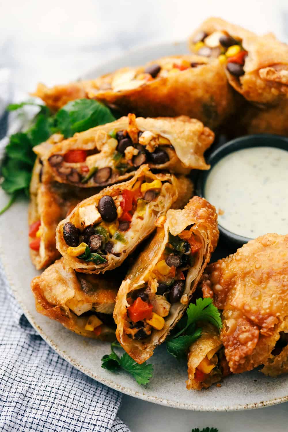 Southwest chicken egg rolls on a plate served with cilantro lime ranch dipping sauce. 