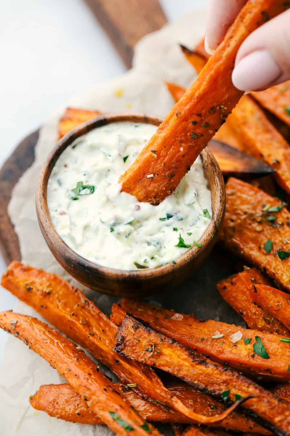 Crispy garlic sweet potatoes being dipped in the avocado ranch dipping sauce. 