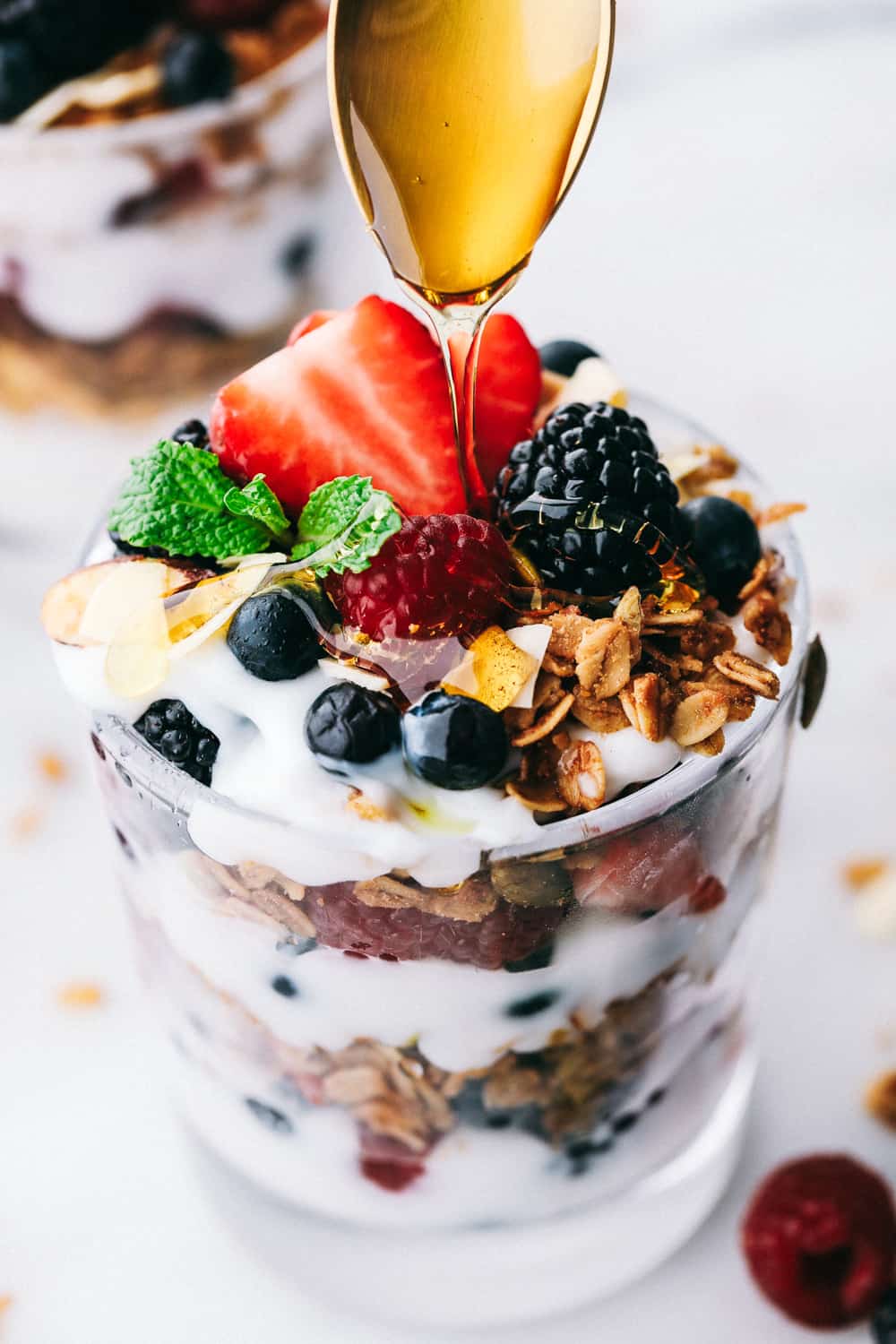 yogurt parfait en una taza de vidrio con miel rociada con una cuchara. 