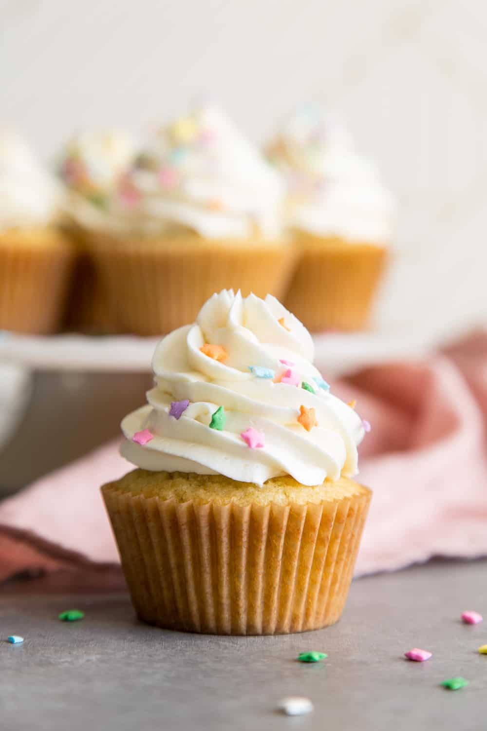 Un cupcake de vainilla con glaseado blanco y chispas de estrellas