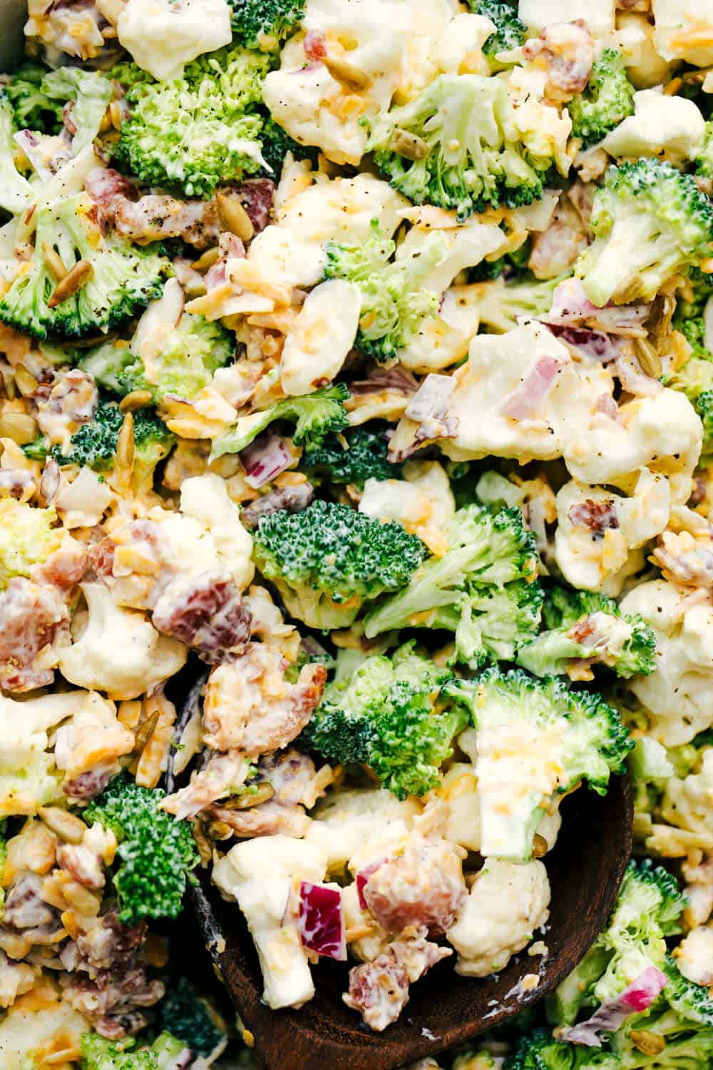 Cauliflower broccoli salad photo with shredded cheese and bacon shown throughout. 