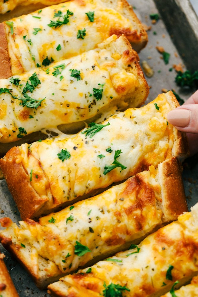 Cheesy garlic bread on a pan being pulled apart.