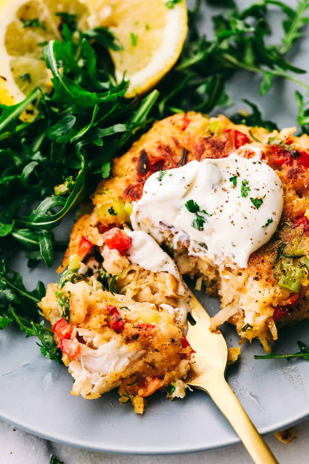 Croquetas de pollo cortadas para un bocado con un tenedor dorado, lechuga y limón a un lado.