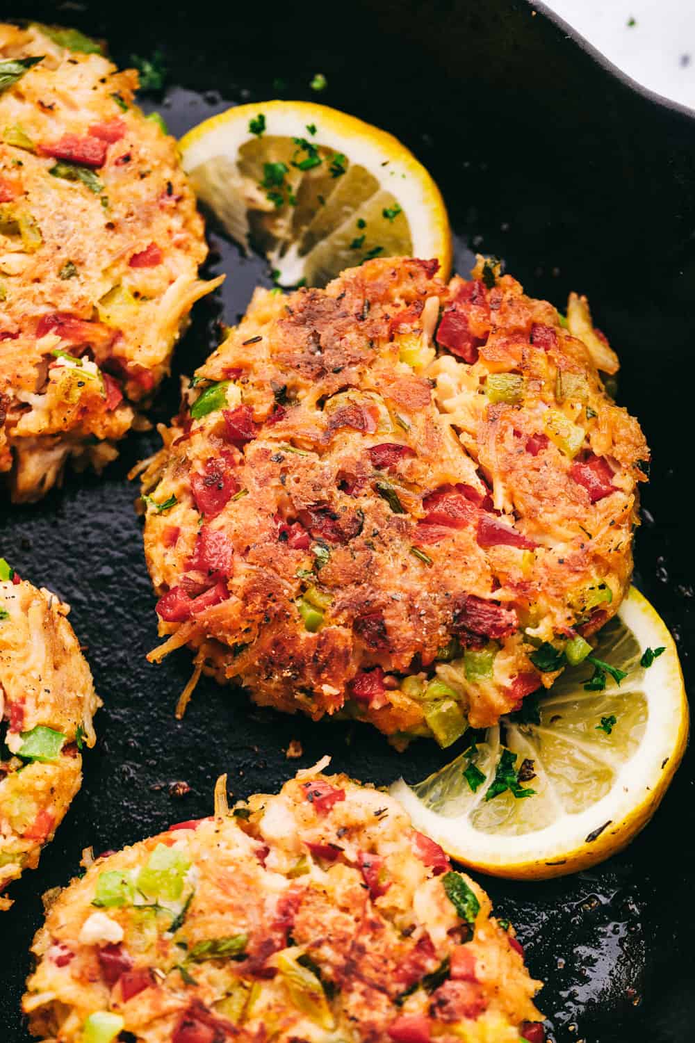 Chicken croquettes on a skillet with lemon being cooked.