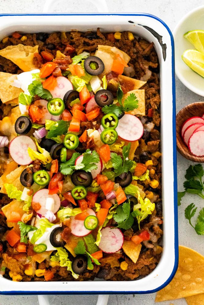 Colorful veggies and chips topped on a casserole dish of ground meat