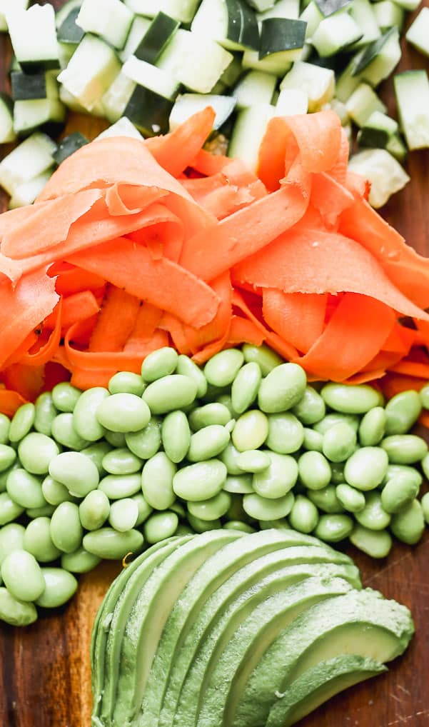 Fruits and vegetables cut up and put in order from zucchini, carrots, peas and avocado. 
