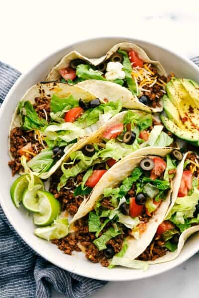 This Homemade Taco Seasoning is so flavorful and takes less than 5 minutes to make. You will never buy taco seasoning from the store again! A plate of soft tacos grilled with meat and topped with shredded cheese, olives, lettuce, tomatoes and sliced avocados.