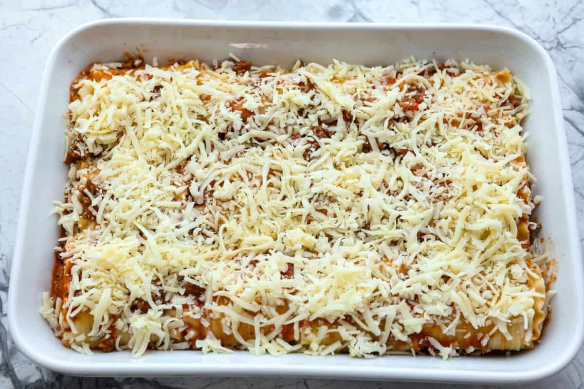 Overhead shot of lasagne roll ups in backing dish with sauce and cheese spread on top. 