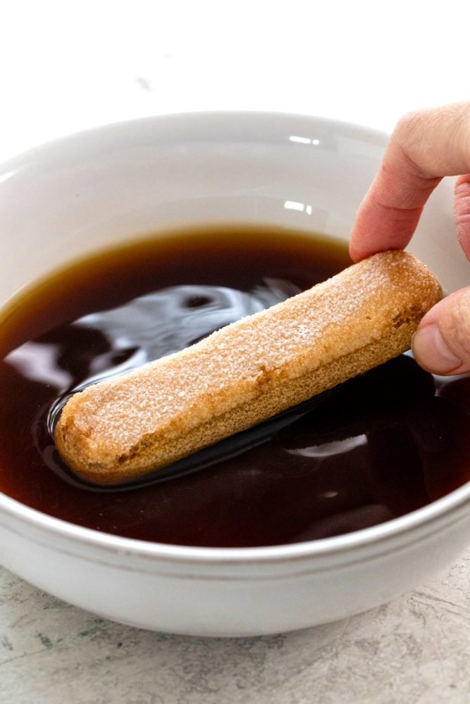 soaking a ladyfinger cookie in a bowl of coffee