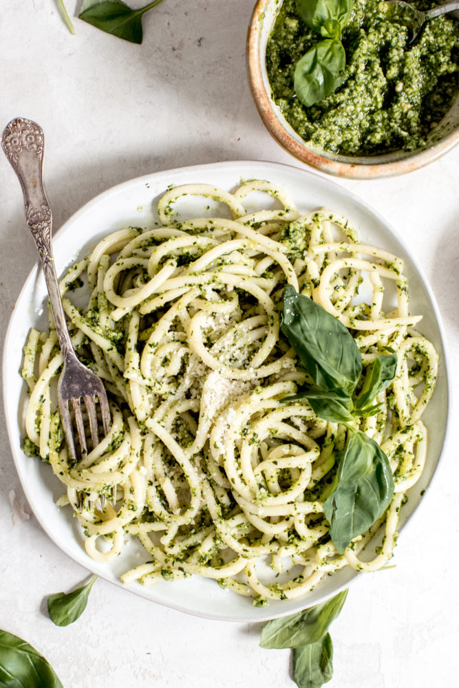 pesto sauce and noodles on white plate with silver spoon