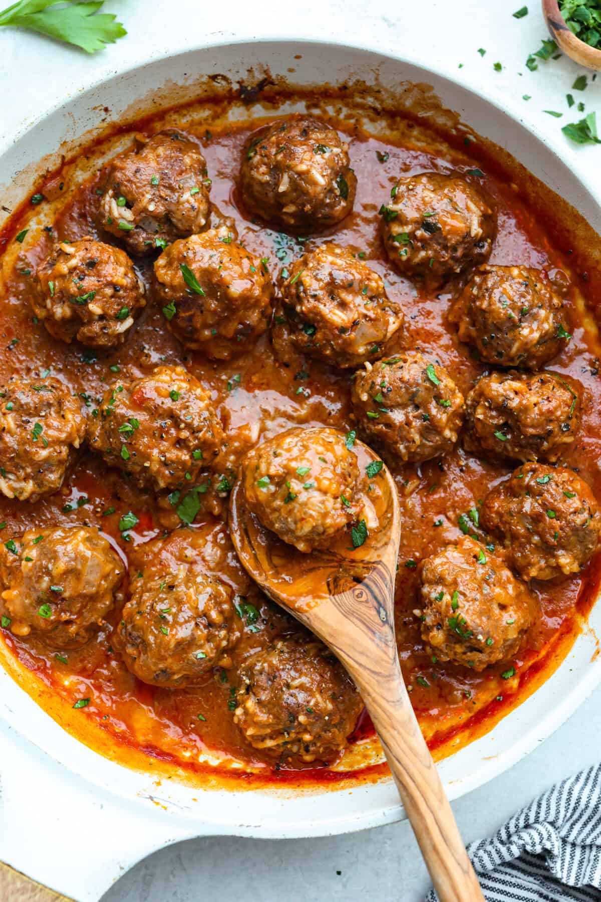 Porcupine balls cooked in a pan with a wooden spoon. 