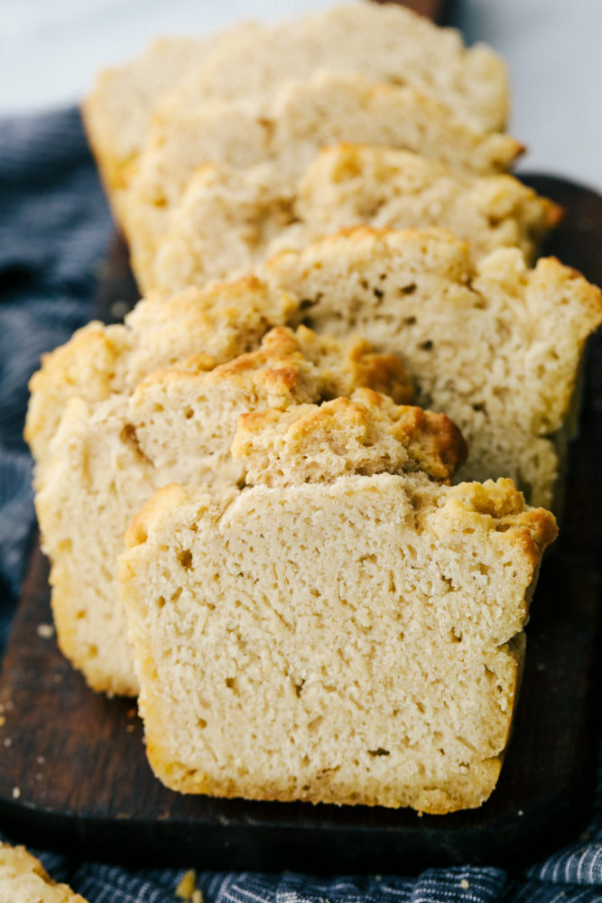 Buttery beer bread sliced up on a cutting board. 