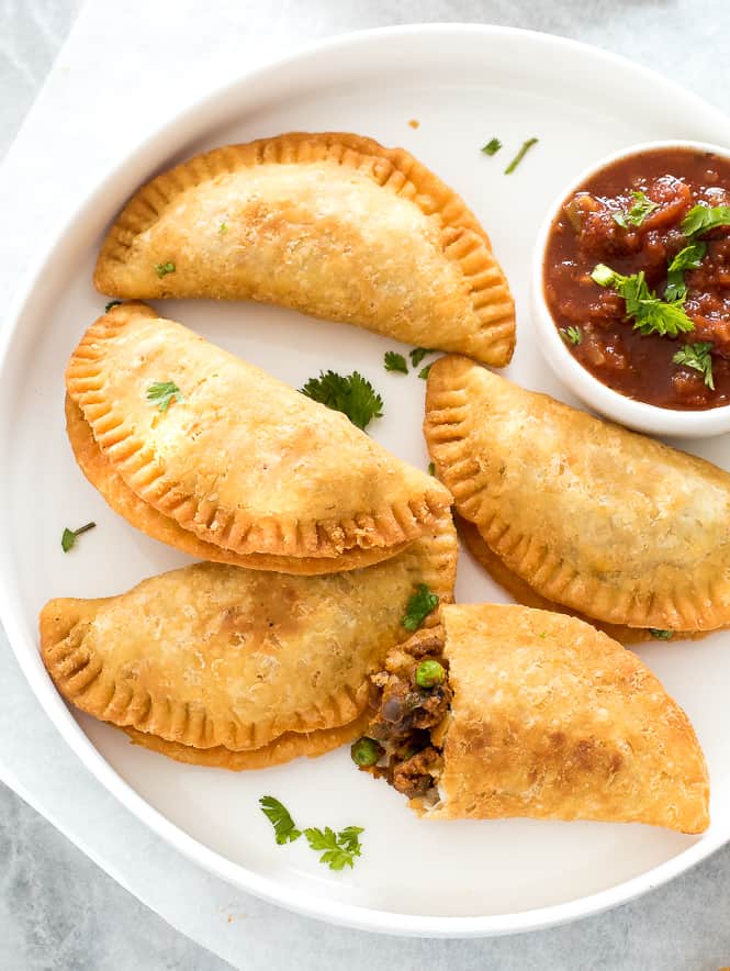 Empanadas on a plate with salsa in a side dish. 