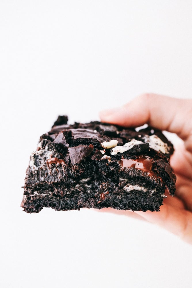 Oreo brownie being held in the air to see the layers of oreo and batter. 