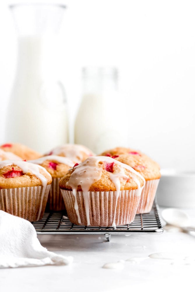 Rhubarb Muffins topped with a glaze on a cooling rack.