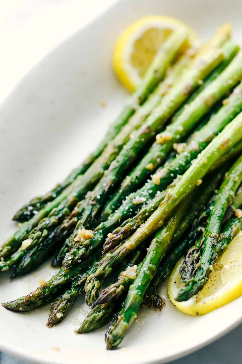 Asparagus placed on a white plate with lemon garnished throughout. 