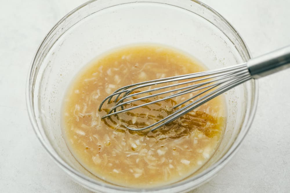 The marinade for the pineapple in a glass bowl with a whisk. 