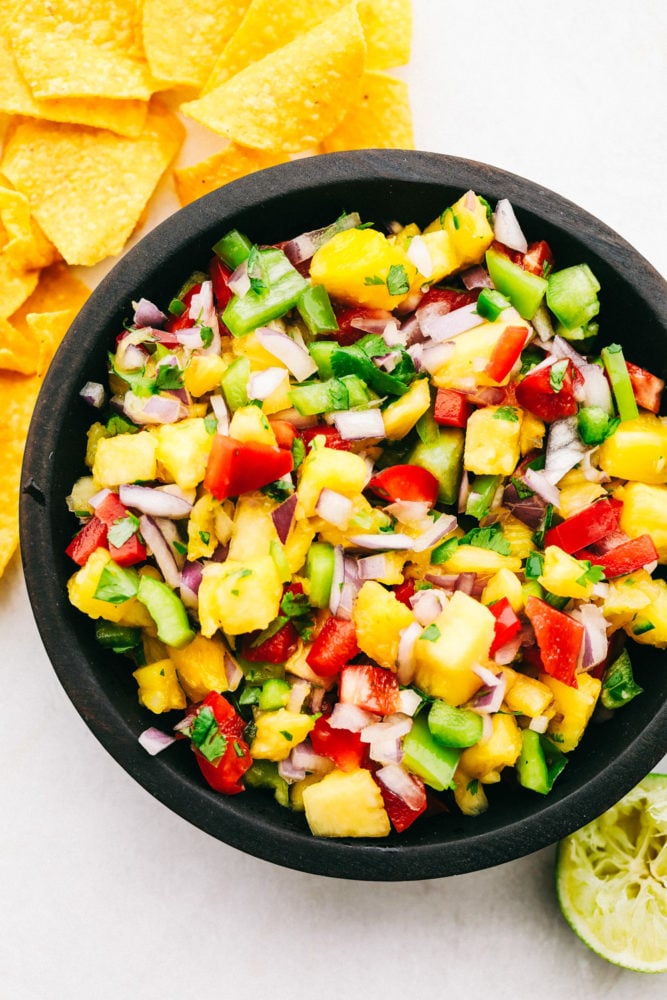 A black bowl filled with pineapple salsa.