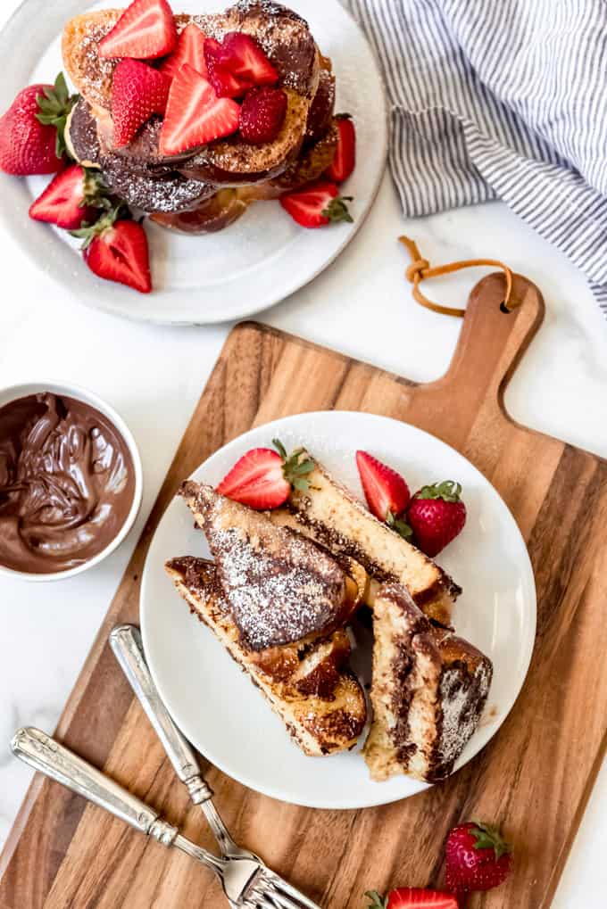 Una imagen de tostada francesa rellena de Nutella con fresas y azúcar en polvo en la parte superior.