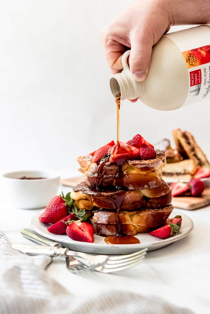 An image of maple syrup being poured over a stack of stuffed french toast