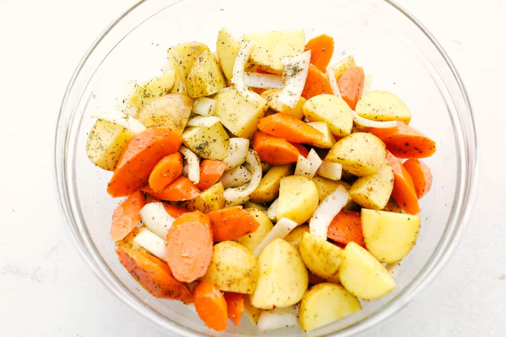 Vegetables in a glass bowl with olive oil and Italian seasoning. 