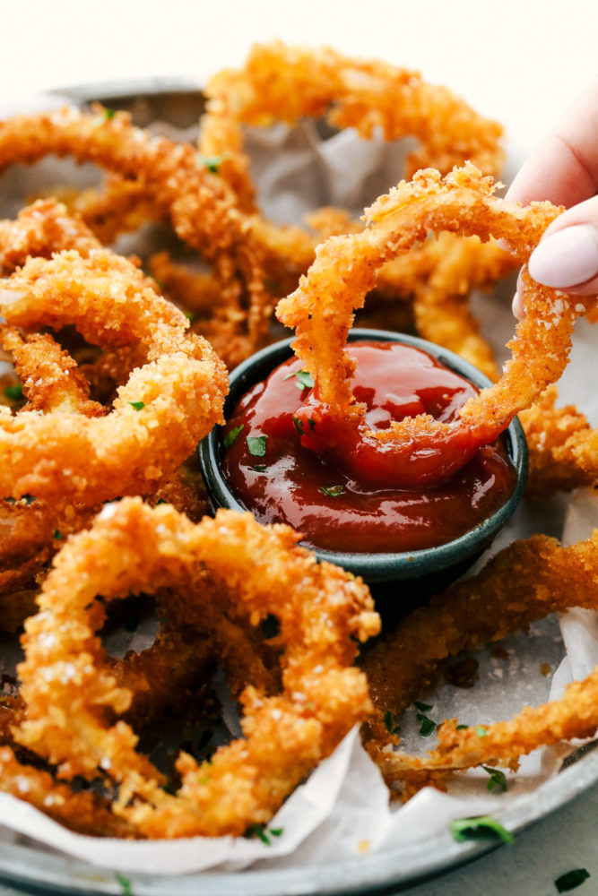 Dipping onion rings in sauce.