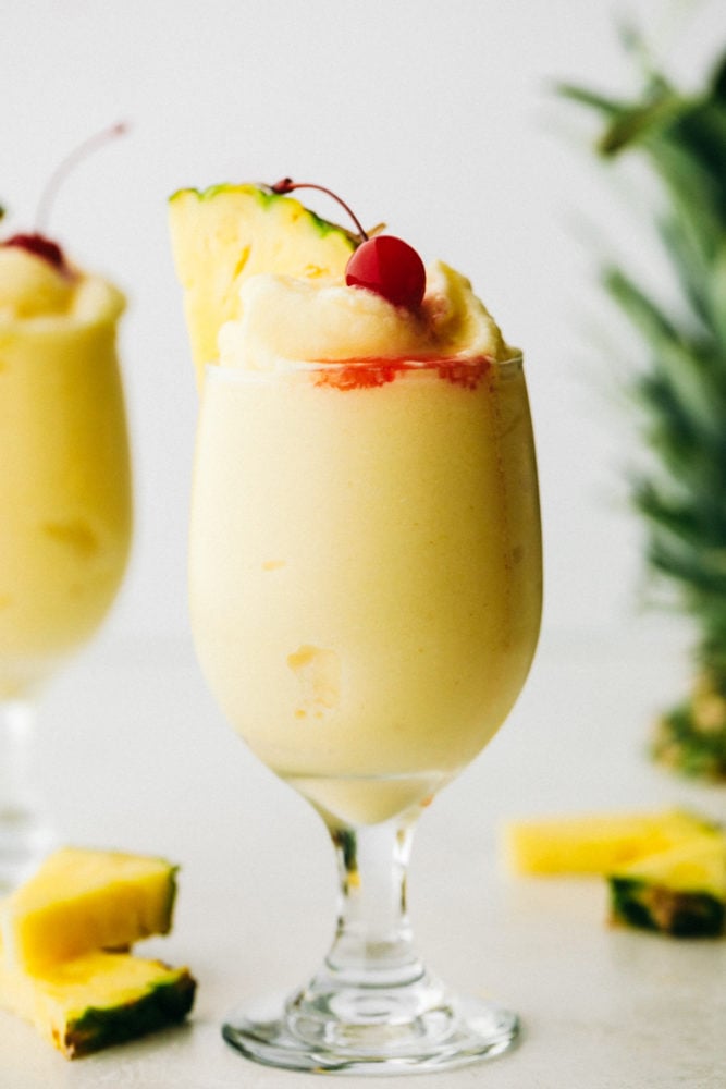 Pina colata garnished with cherry and pineapple slice.