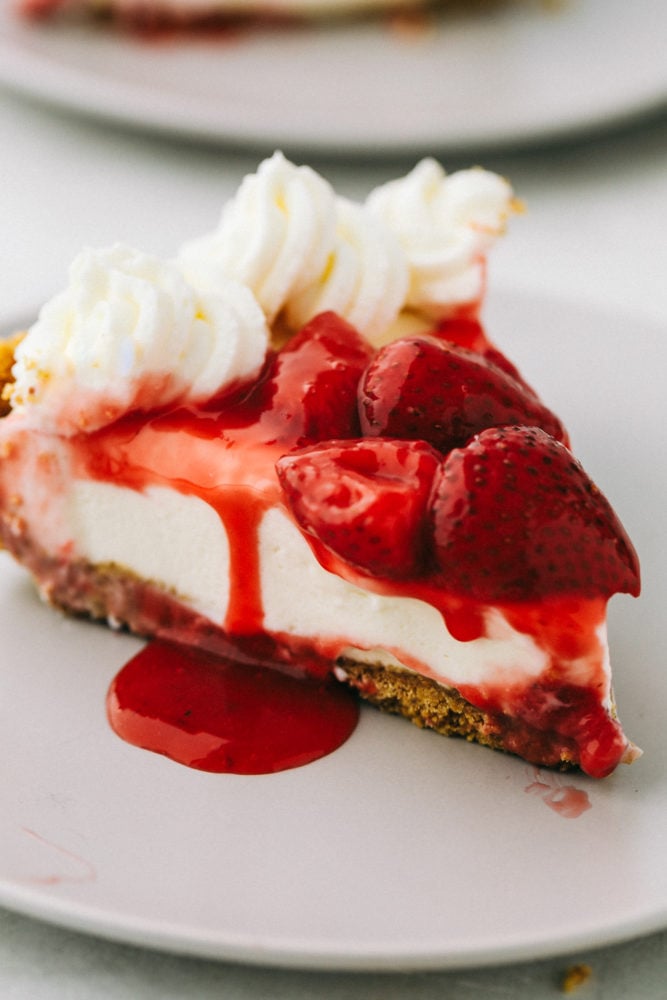 Finished no bake cheese cake topped with whipped cream strawberry syrup and strawberries.