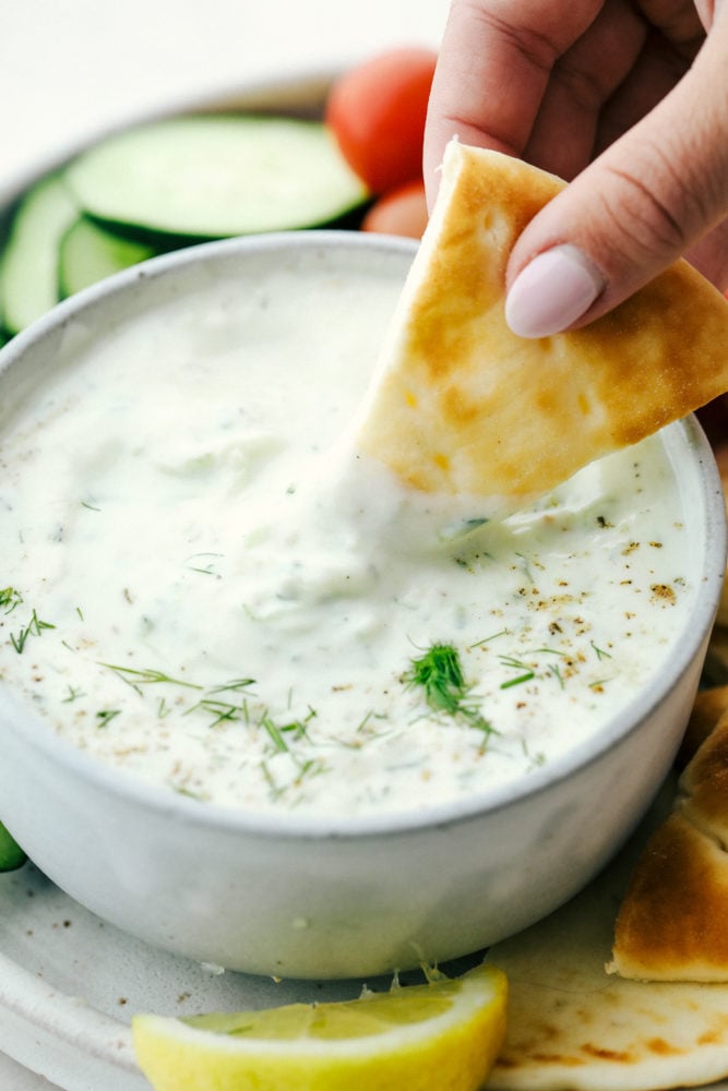 Dipping a chip in Tzatziki sauce.