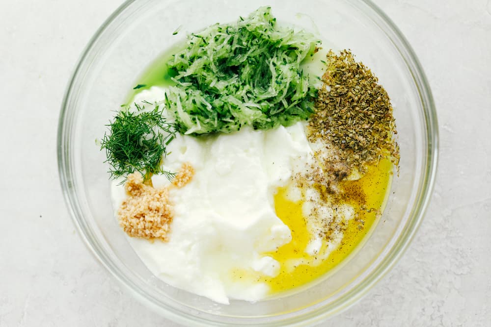 Ingredients for Tzatziki sauce in a clear bowl.