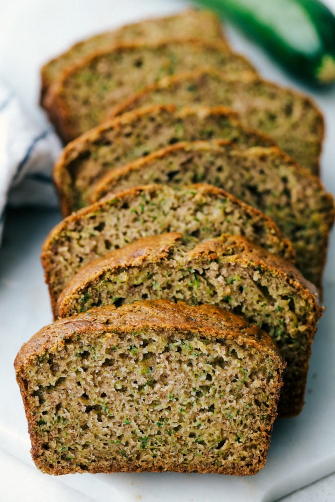 Zucchini bread sliced up in a photo on a white plate. 